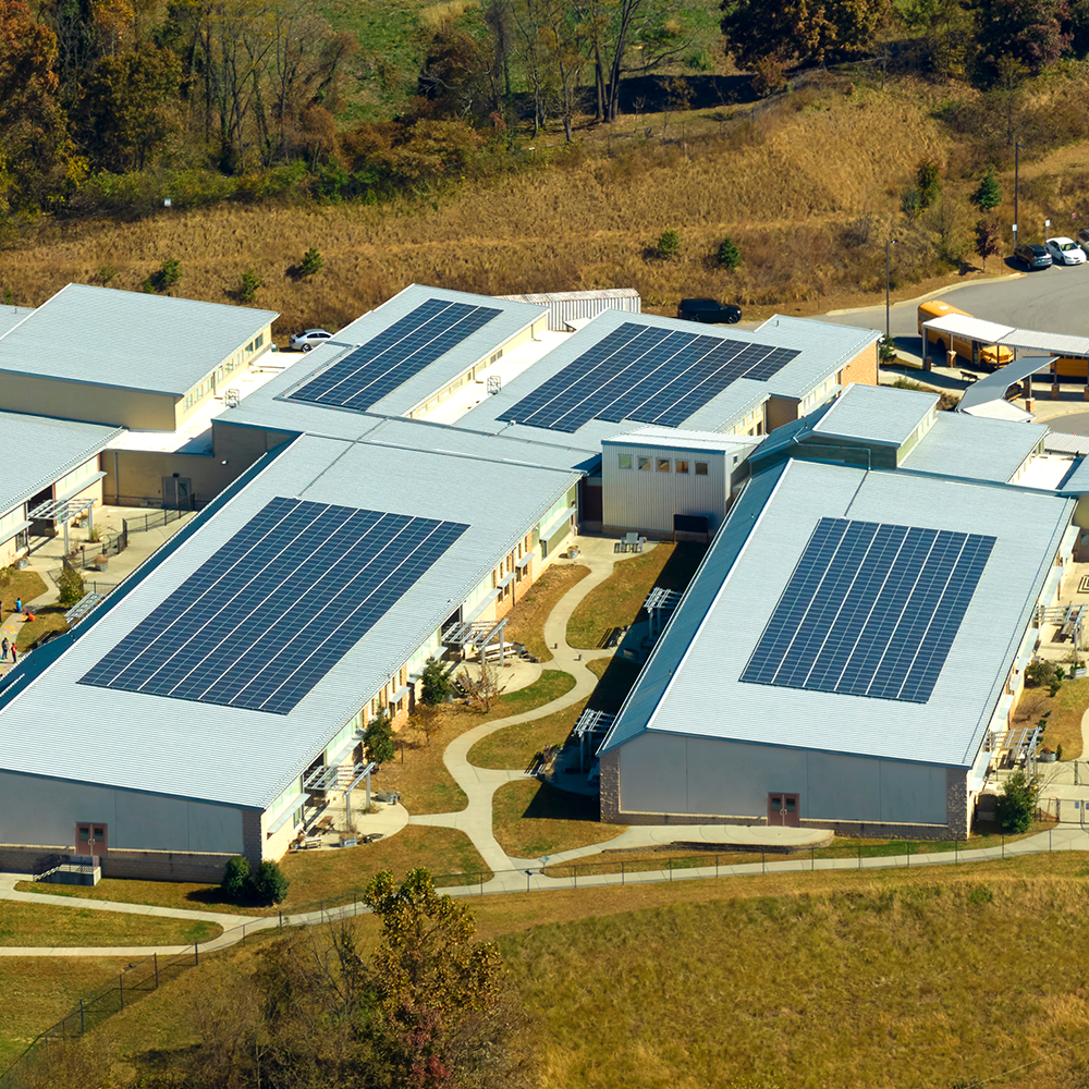 Aerial view of a large commercial or public building with flat roof solar panel installation — ideal for schools and businesses in Bicester exploring solar energy